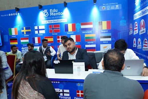 Students seated for consultations at the Edu Mentor booth wall of flags