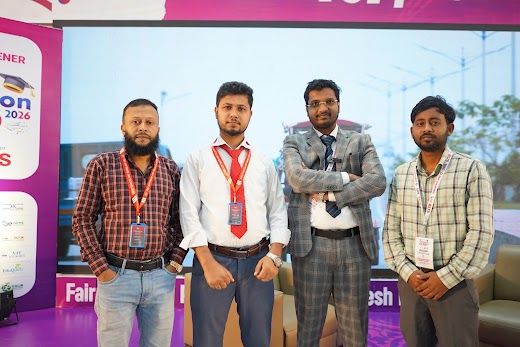 Posed group of four exhibitor staff in front of the event backdrop
