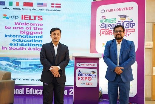 Two exhibitor representatives posed beside the Fair Convener podium on the branded stage